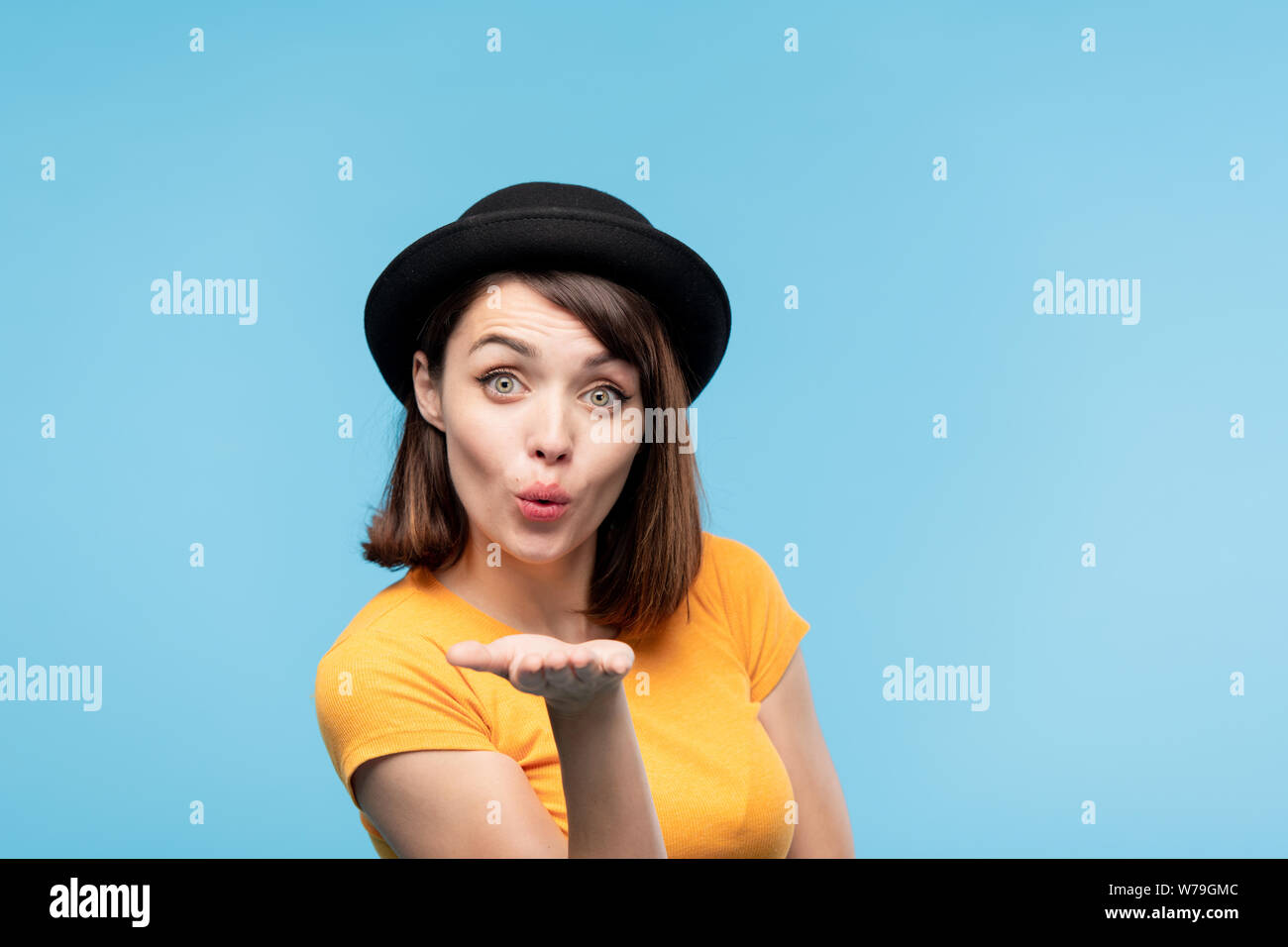 Flirty brunette Mädchen in schwarzen Hut senden Sie Luft kiss Stockfoto