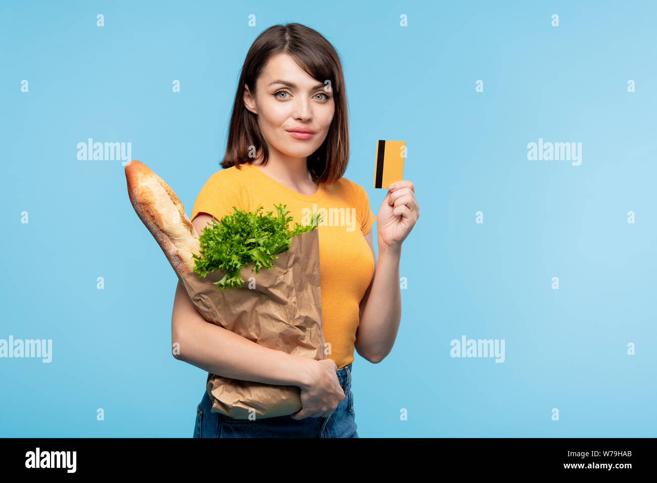 Hübsche junge Verbraucher mit Lebensmitteln zeigt Ihre Kreditkarte Stockfoto