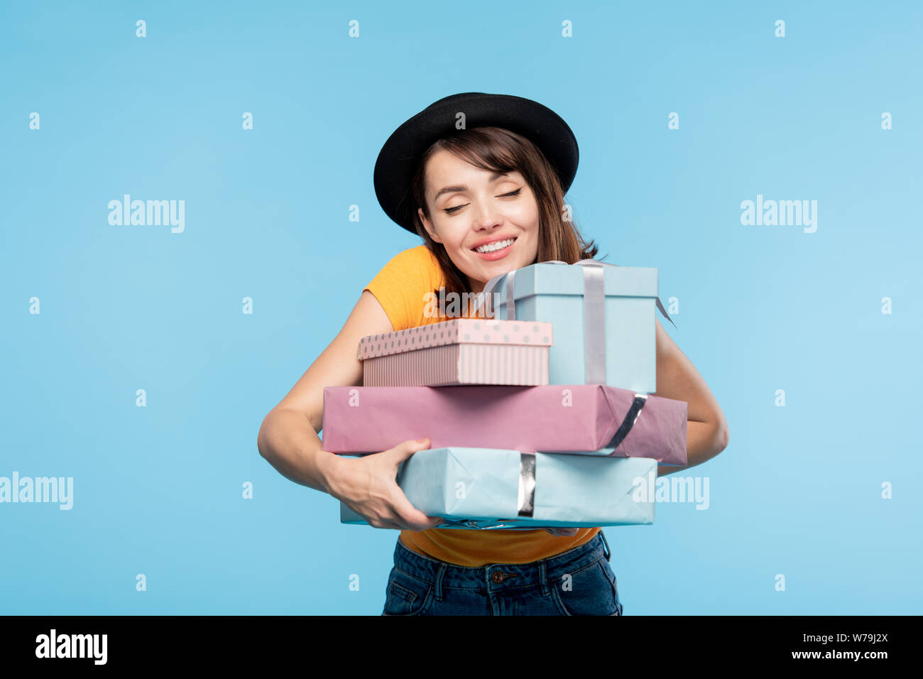 Junge fröhliche Frau in hat umarmt von verpackten Geschenke Stapel Stockfoto