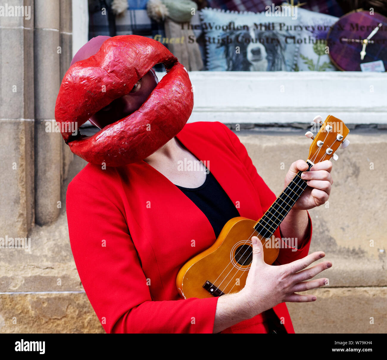 Eine Street Performer mit großen roten Lippen und ein ukelele Edinburgh Festival Fringe 2019 - The Royal Mile, Edinburgh, Schottland, Großbritannien. Stockfoto