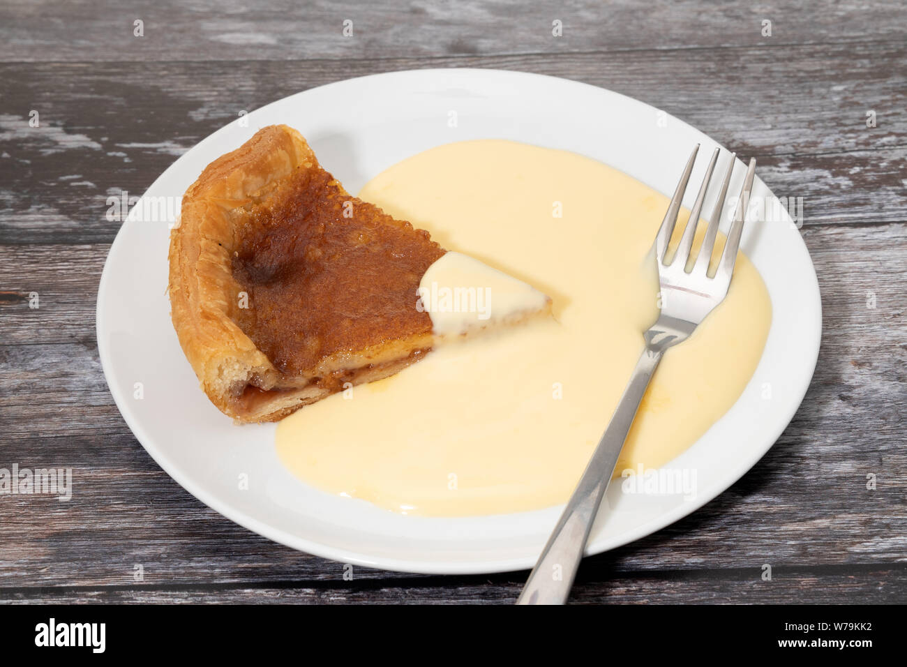 Ein original Bakewell tart Pudding auf Teller serviert mit Vanillesauce Stockfoto