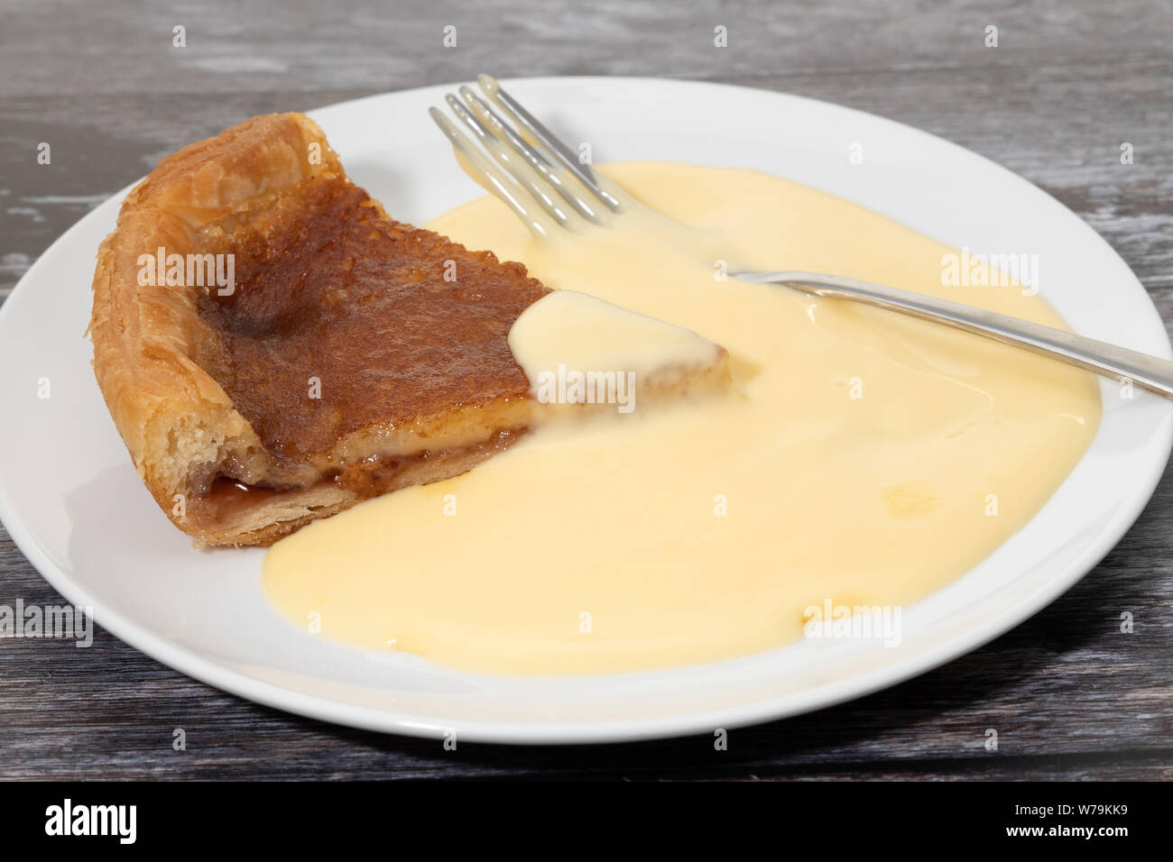 Ein original Bakewell tart Pudding auf Teller serviert mit Vanillesauce Stockfoto