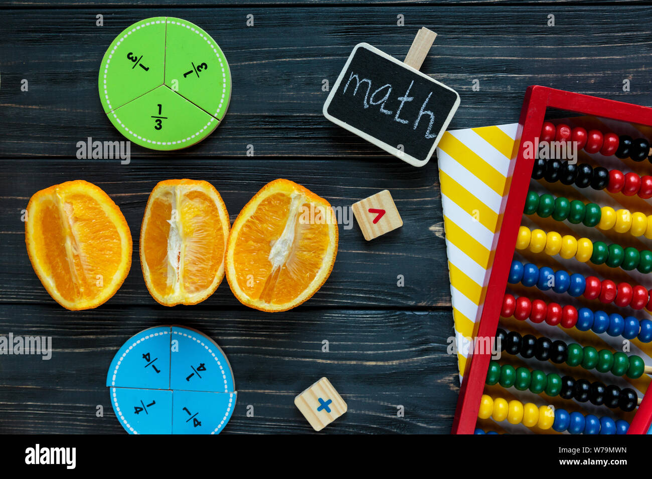 Сolorful mathe Fraktionen und Orangen als Probe auf dunklem Hintergrund oder Tabelle. Interessante kreative lustige Mathe für Kids. Bildung, zurück zu schoo Stockfoto