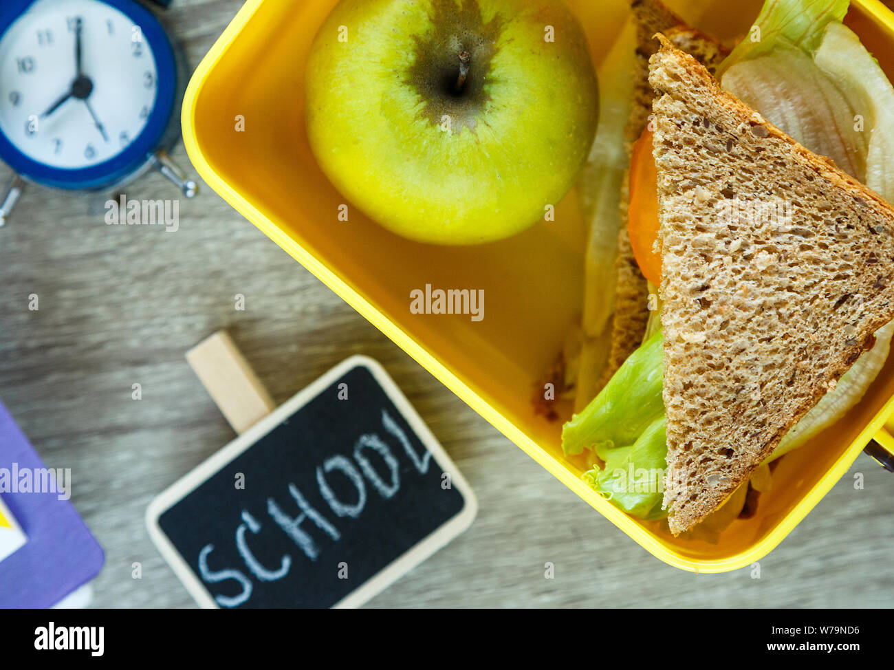 Schule gelb Lunch Box mit Sandwich, grüner Apfel, am schwarzen Brett. Gesunde Ernährung in der Schule. Zurück zu Hintergrund Schule. Flach, Ansicht von oben. Stockfoto