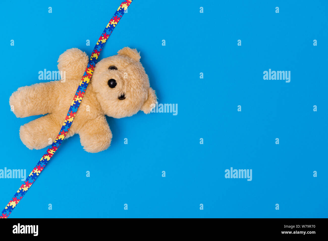 Welt Autismus Bewußtsein Tag, psychische Gesundheit Konzept mit Teddybär und Farbband puzzle Muster. Auf blauem Hintergrund Stockfoto