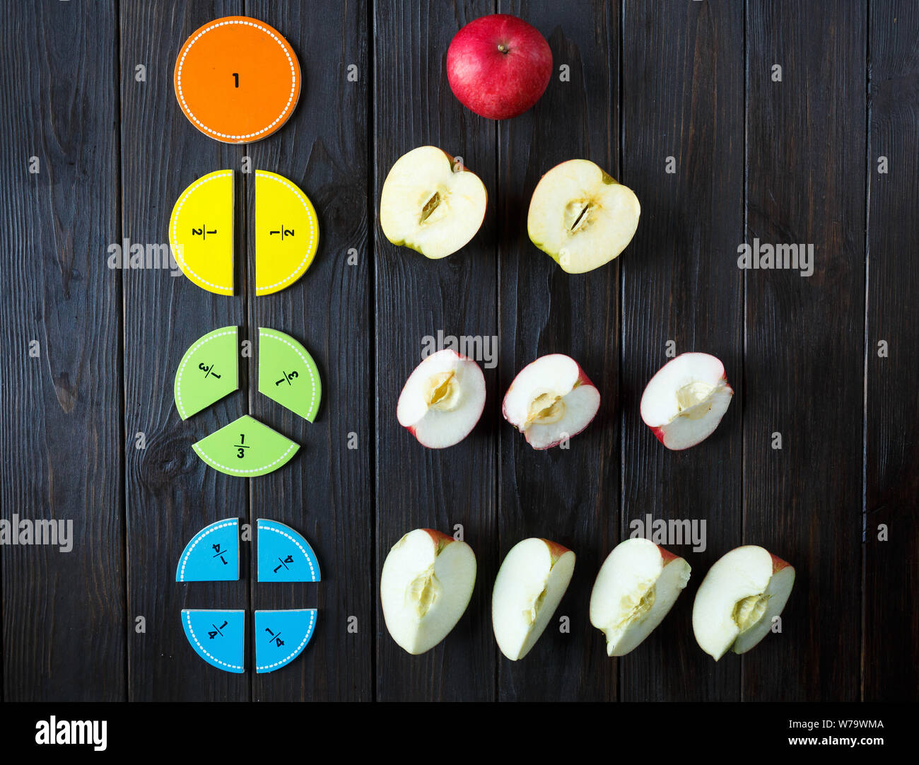 Bunte mathematische Fraktionen und Äpfel als Probe auf braunem Holz- Hintergrund oder Tisch. interessante Mathe für Kids. Bildung, zurück in die Schule. Stockfoto