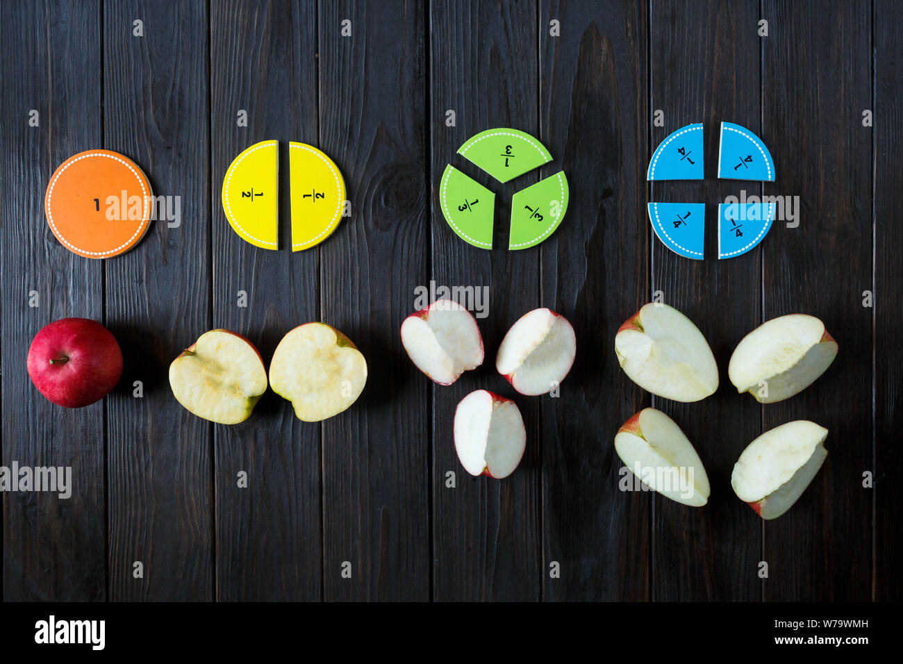 Bunte mathematische Fraktionen und Äpfel als Probe auf braunem Holz- Hintergrund oder Tisch. interessante Mathe für Kids. Bildung, zurück in die Schule. Stockfoto