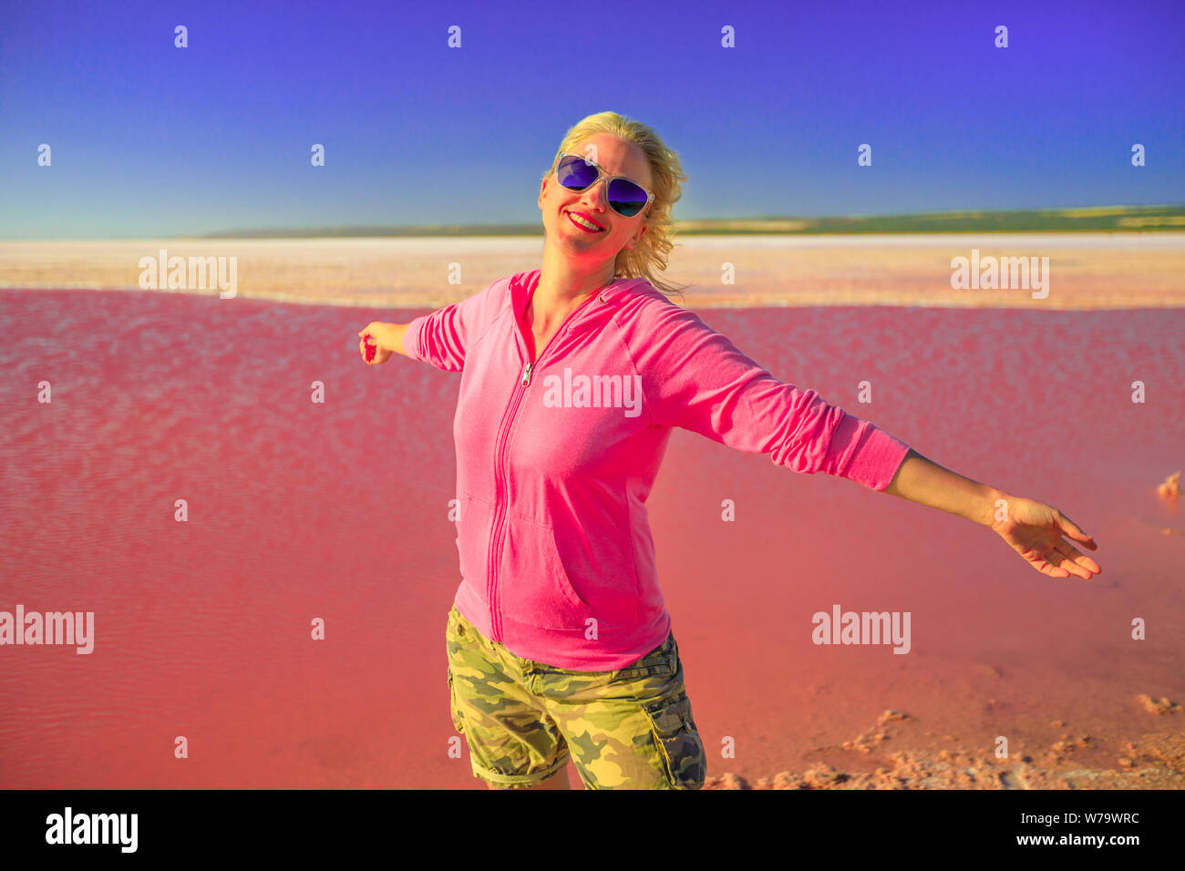 Freiheit kaukasische Frau mit offenen Armen am Pink Lake in Port Gregory, Westaustralien. Blonde Touristen in Hutt Lagoon, Australien. Blauer Himmel im Sommer Stockfoto