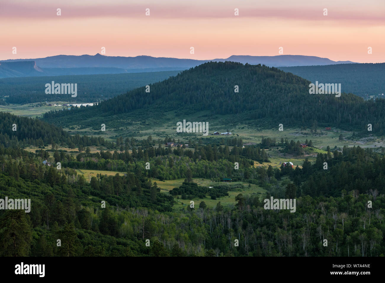 Luftaufnahme von einer ländlichen Landschaft der Täler, Felder, Bauernhöfe, Hügeln und Bergen unter einem schönen Himmel bei Sonnenuntergang in der Nähe von Pagosa Springs, Colorado Stockfoto