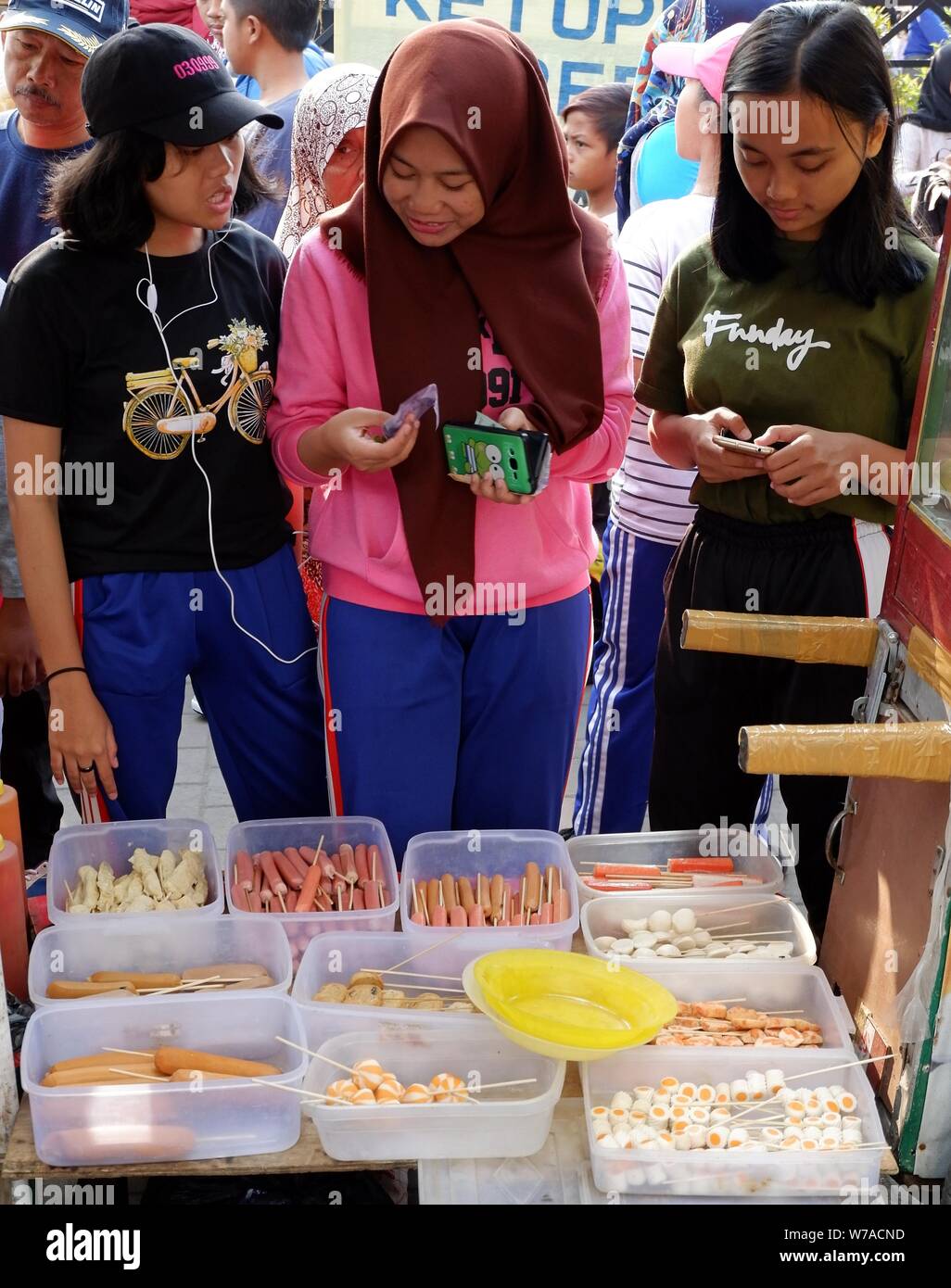 Drei indonesischen Jugendmädchen haben eine Diskussion vor einem Street Food stall. Stockfoto