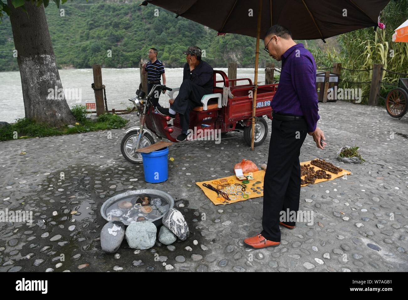 Ein Tourist sieht sich die Steine mit Tier-förmiges Muster auf ihre Oberflächen in der Nähe der Dadu River in Shimian county angezeigt, Ya'an City, Südwesten Kinn Stockfoto
