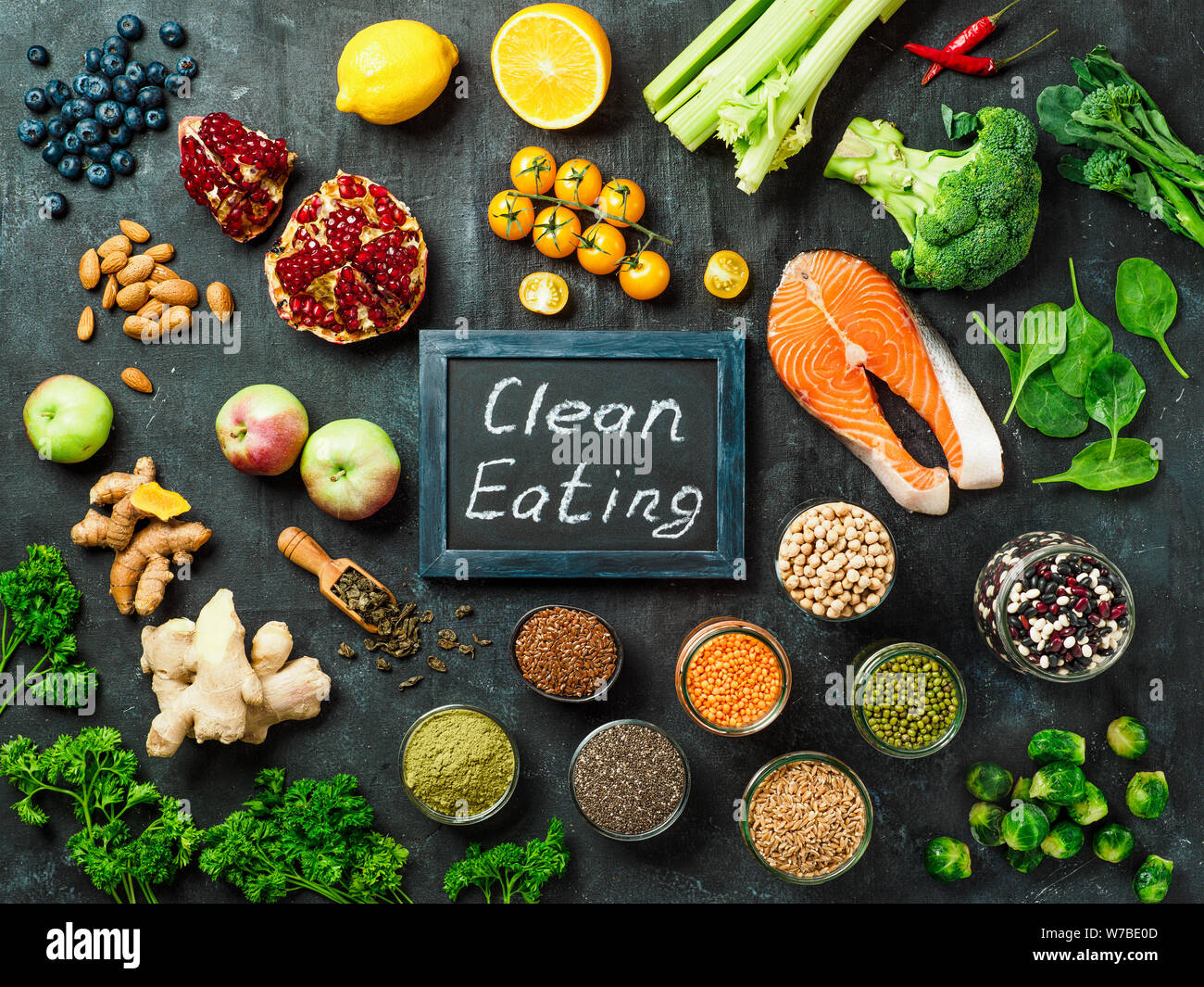 Sauber Essen Konzept. Auswahl Lebensmittelzutaten und Schiefertafel mit Sauber Essen Worte auf dunklem Hintergrund. Top View oder flach. Stockfoto
