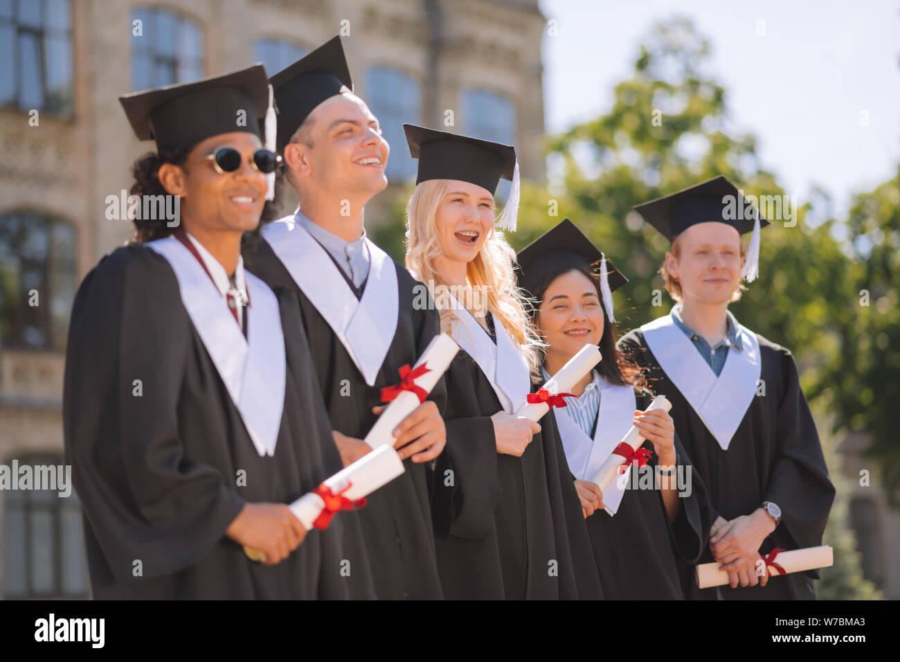 Fröhliche Studenten warten auf ihren Abschluss von der Universität. Stockfoto
