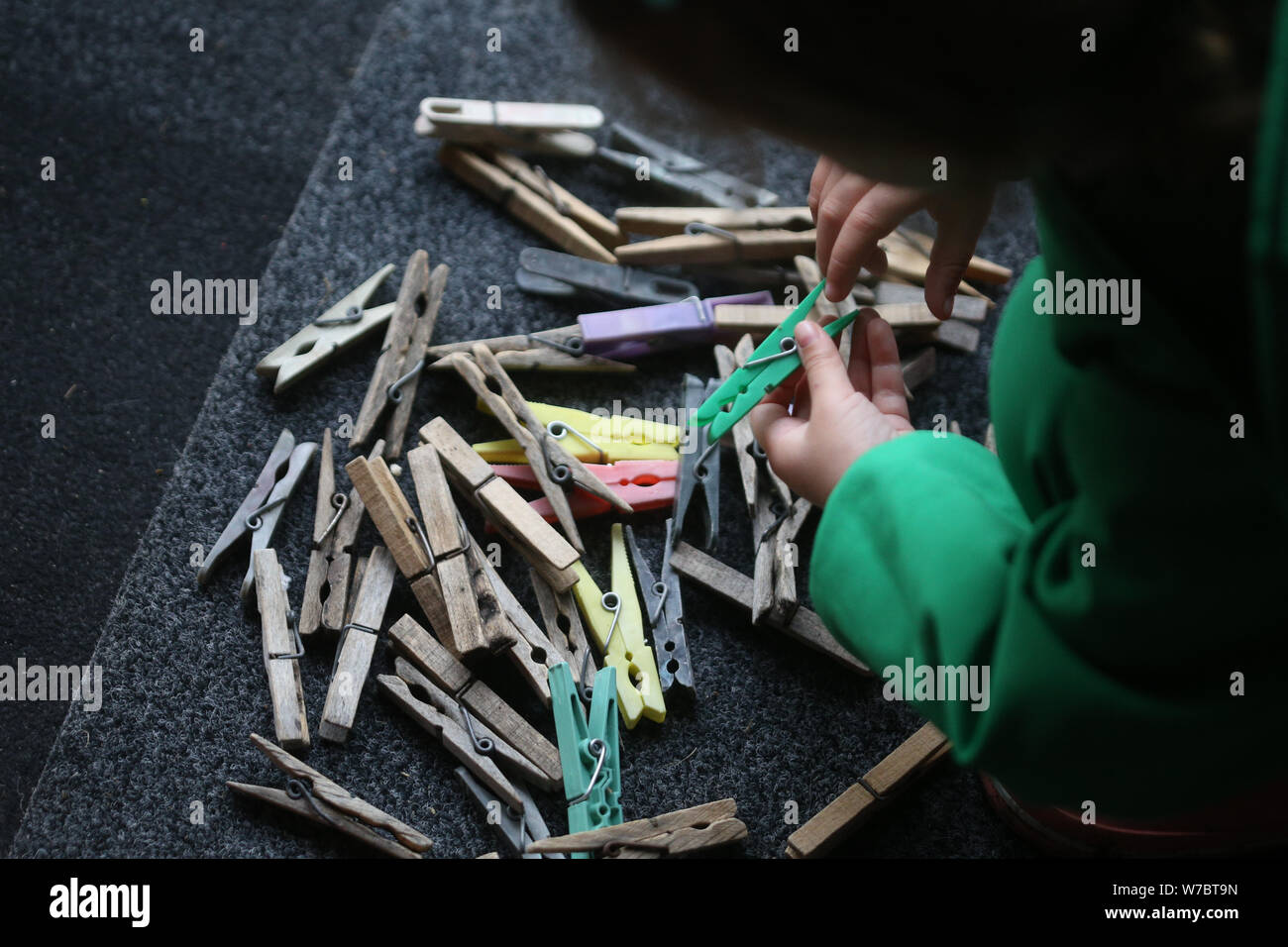 Details mit den Händen ein kleines Mädchen spielen mit Kunststoff- und Wäscheklammern am Draht Stockfoto