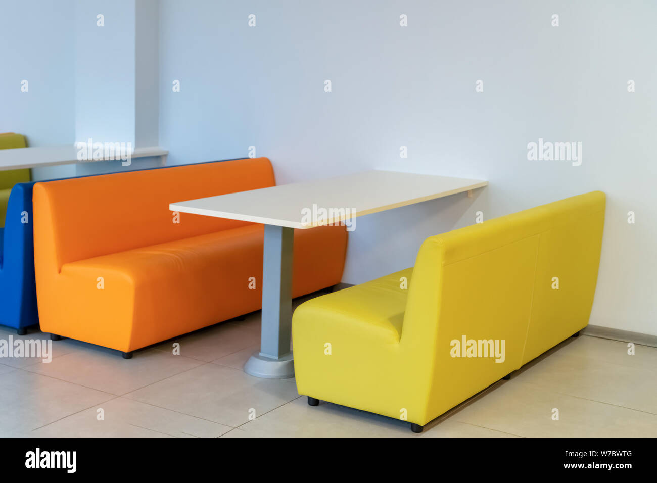 Russland, Tatarstan, 13. April 2019. Zwei bunte Sessel Sofas mit einem Tisch im Zimmer. Gelb und Orange Bänken. Interior Design. Schule. Stockfoto