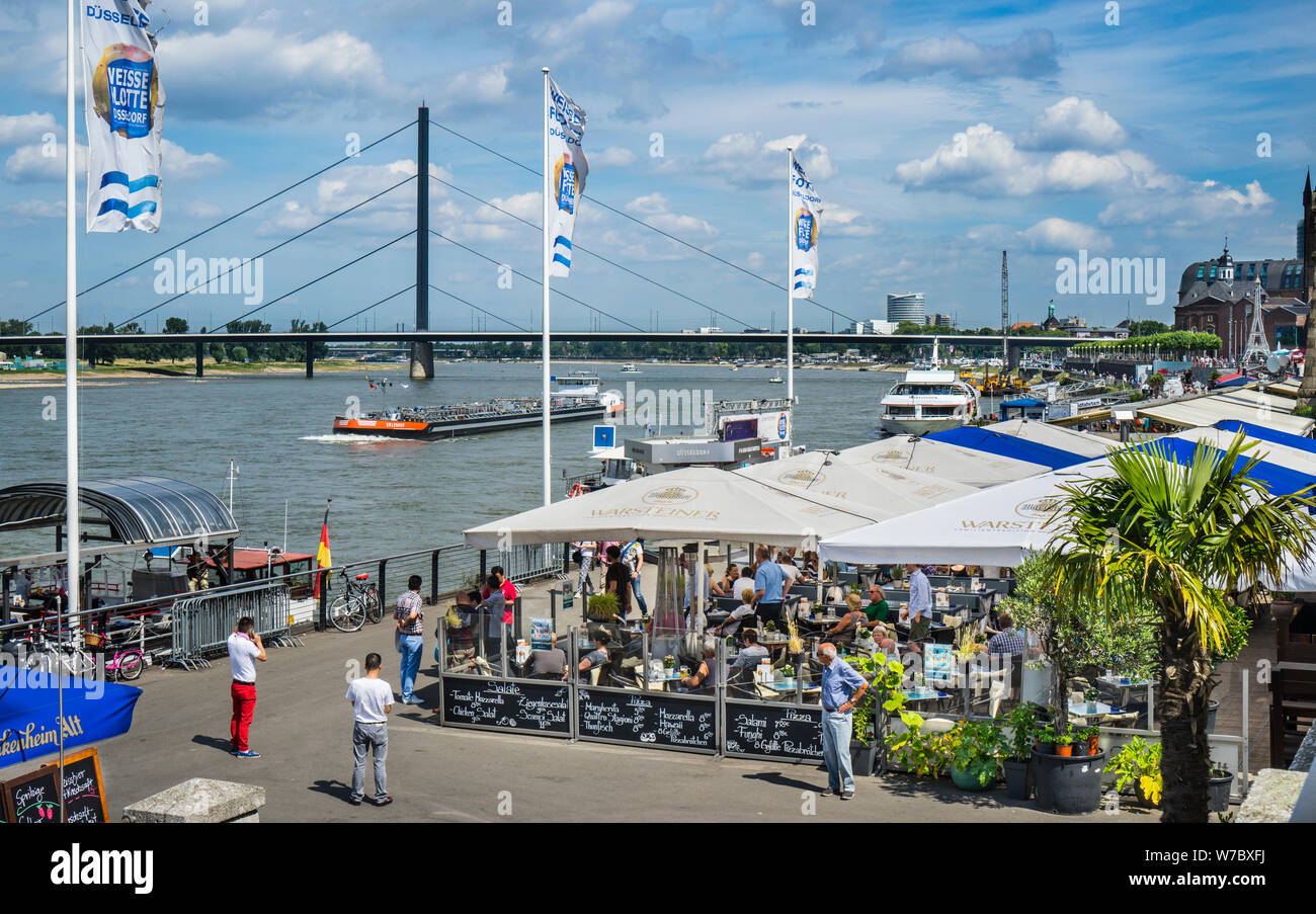 Waterfront von Düsseldorf Rheinuferpromenade am Rathausufer mit Biergärten und Restaurants und Blick auf die Oberkasseler Brücke, Düsseld Stockfoto