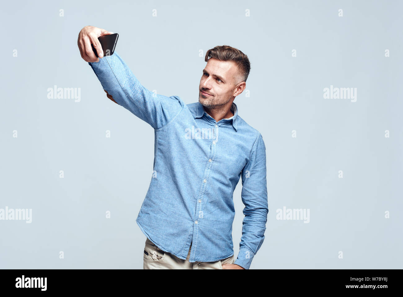 Fangen glückliche Momente fröhlich und gut aussehend bärtigen Mann in Casual tragen Selfie beim Stehen vor grauem Hintergrund. Digitales Konzept. Positive Emotionen. Fotografie Stockfoto