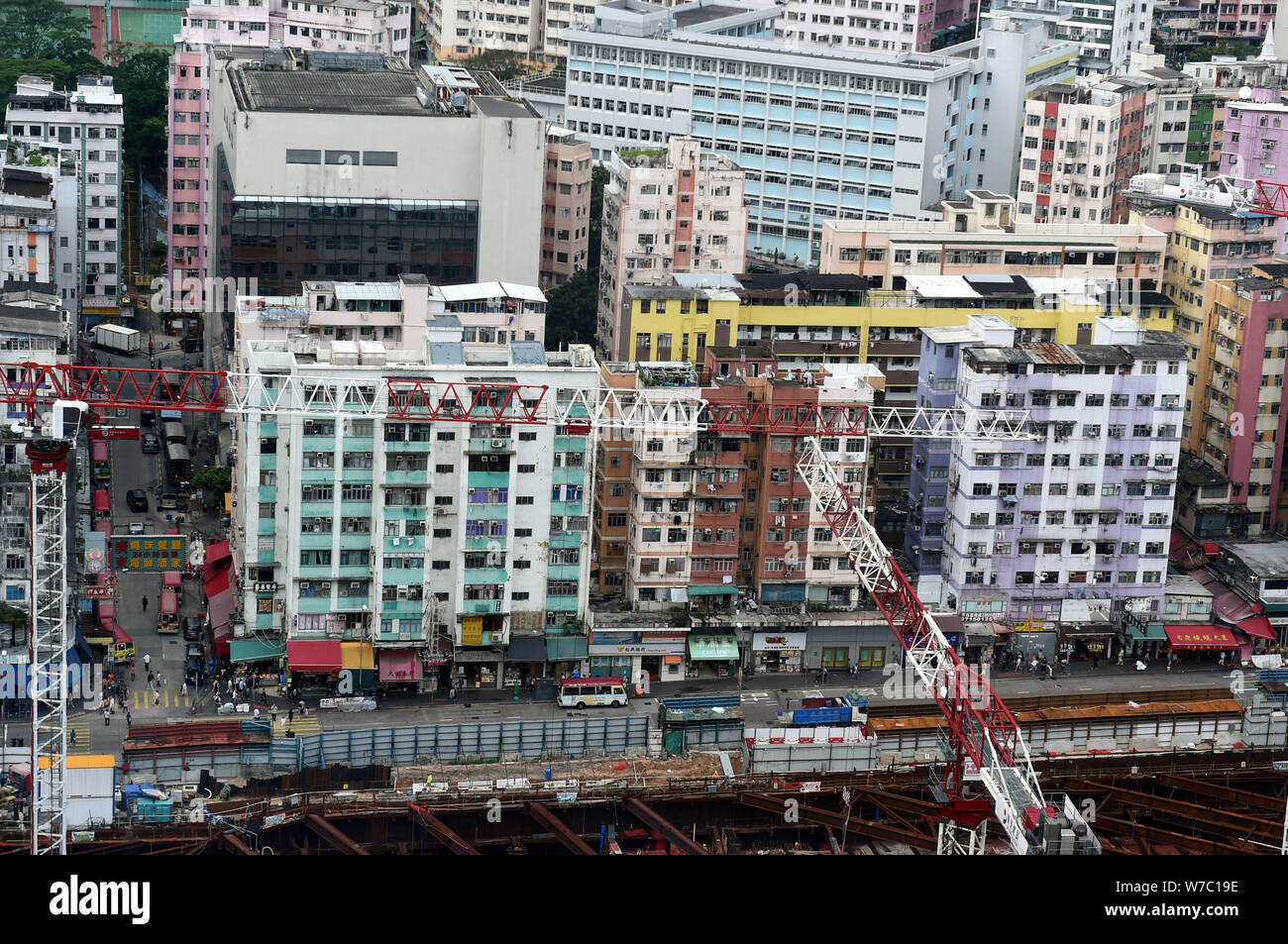 Turmdrehkrane Arbeit auf einer Baustelle in Kwun Tong, einem der ältesten Viertel in Hong Kong, mit alten und neuen Hochhäusern in der Rückseite Stockfoto