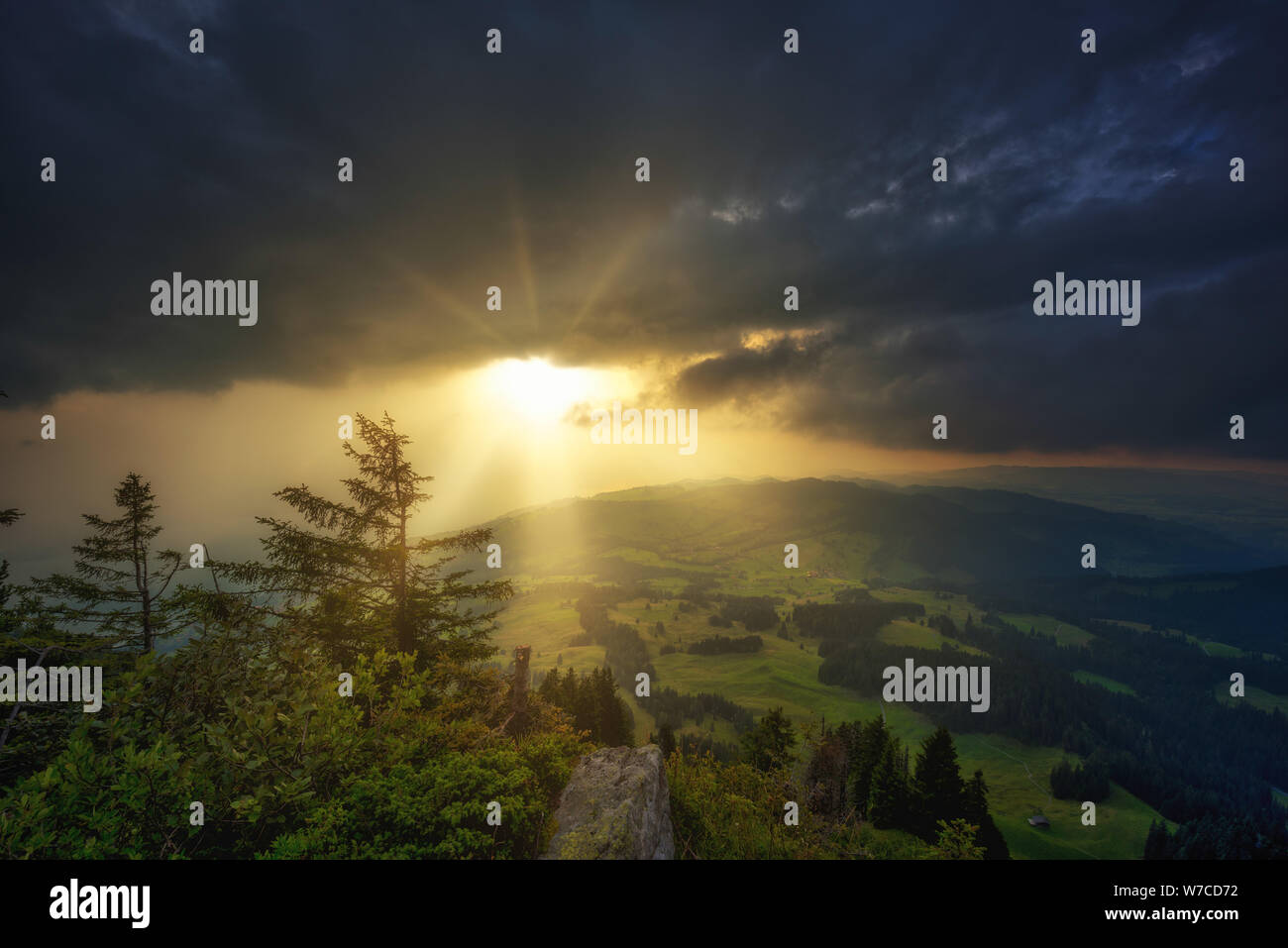 Sonnenuntergang unter dunklen Wolken, die von einem Berg Crest (Sigriswilergrat) bis zu Wäldern und Wiesen gesehen Stockfoto