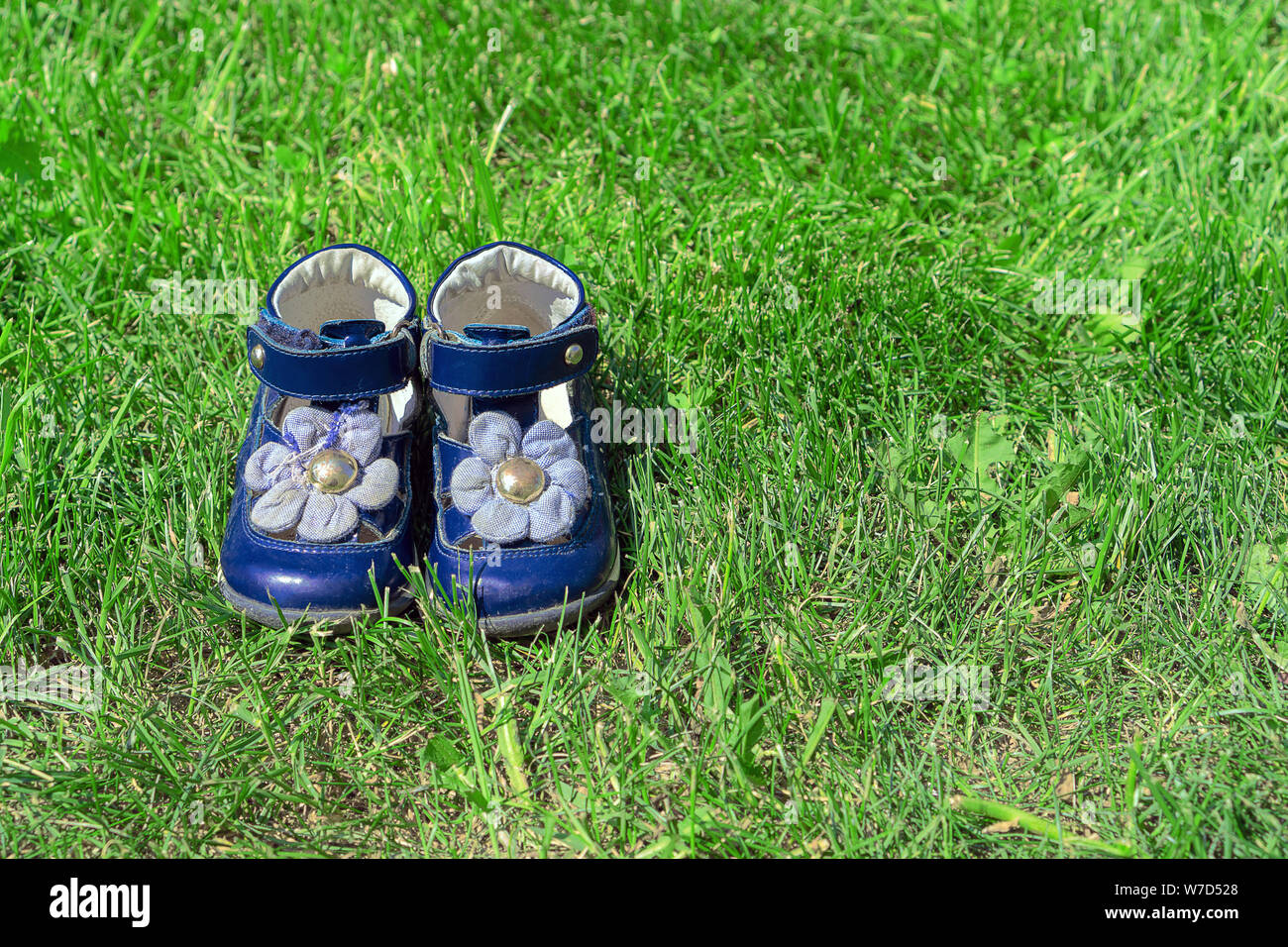 Kinder Blue's Sandalen auf grünem Gras. Die niedliche Mädchen Schuhe in den Garten. Das Konzept im Sommer. Stockfoto