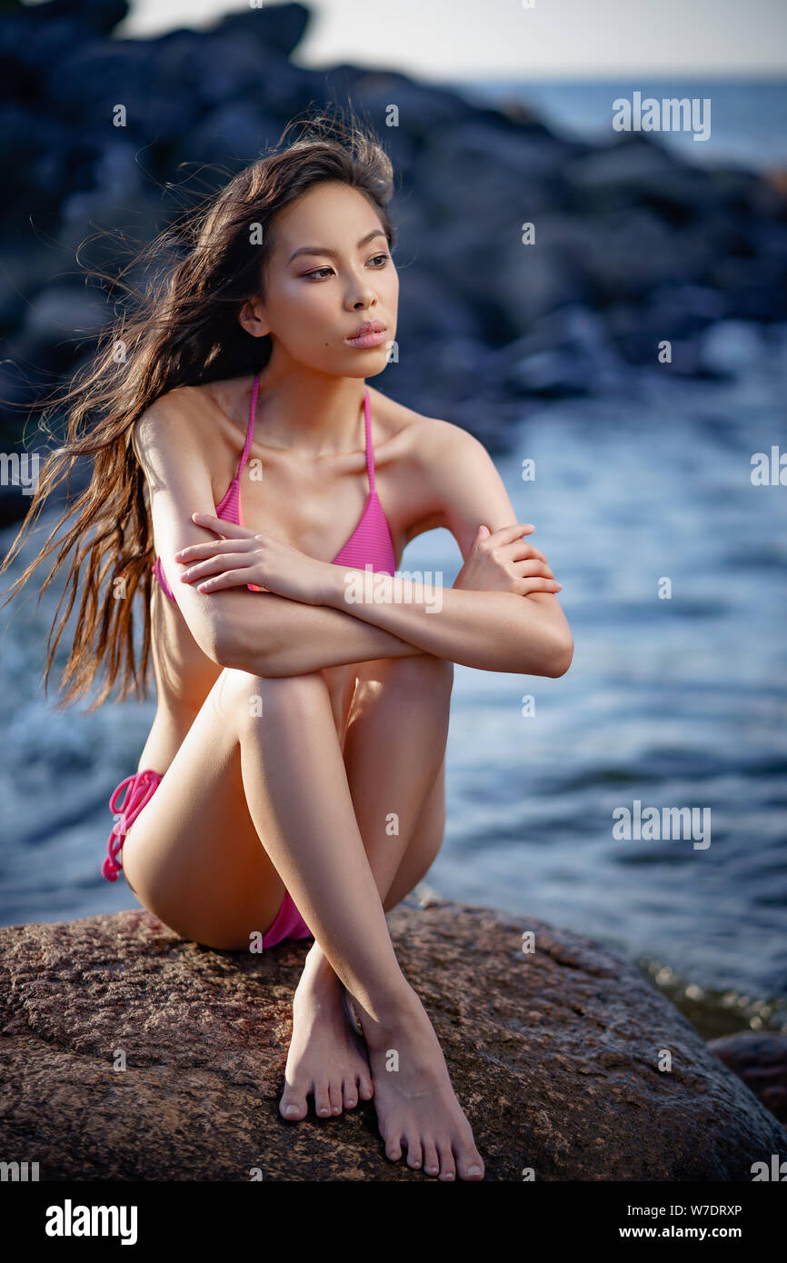 Konzept: Tourismus, Urlaub, Reisen. Junge schlanke hübsche Asiatin in zwei Stücken rosa Badeanzug am Strand entspannen. Fashion Fotoshooting. Stockfoto