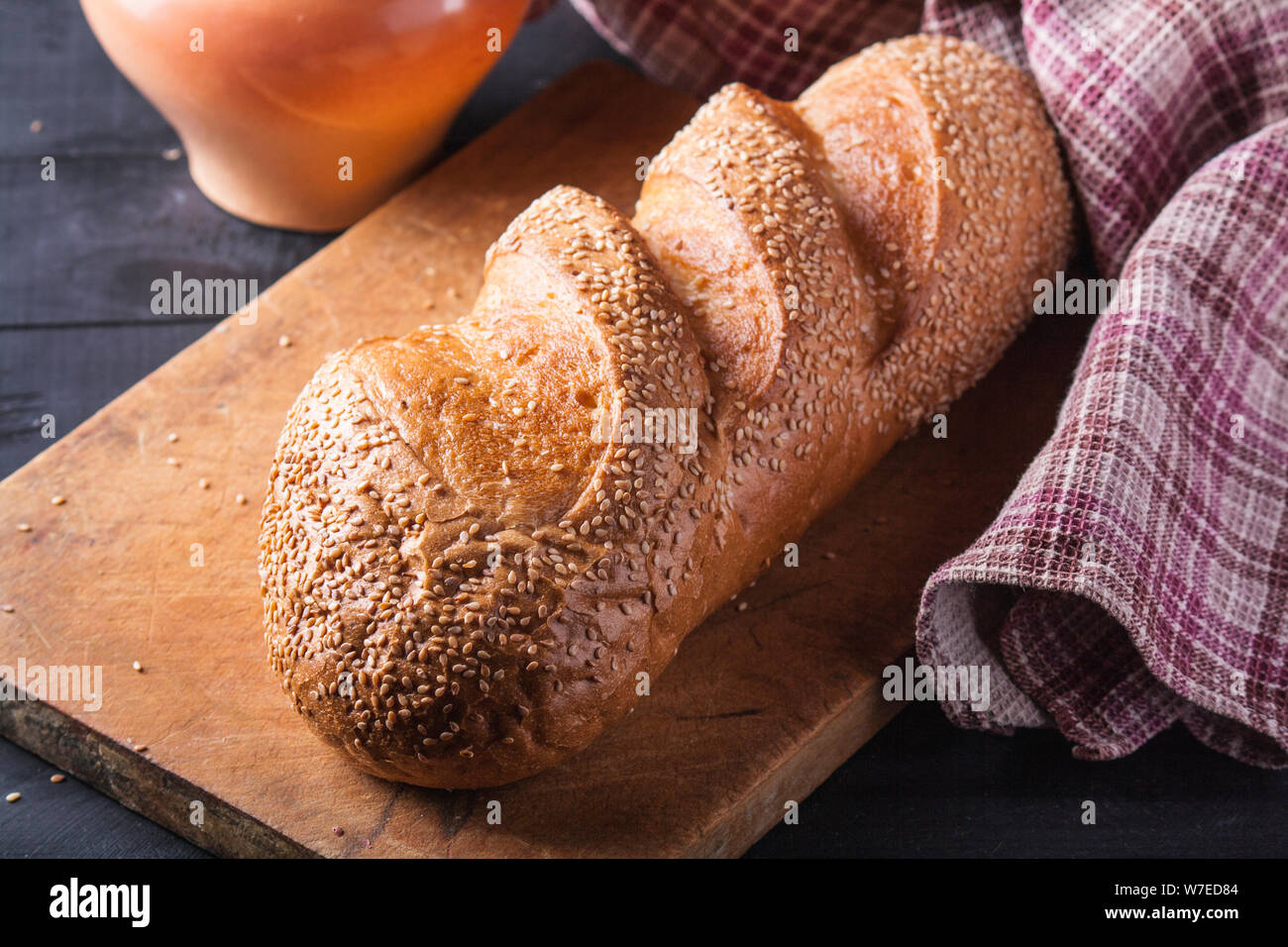 Frisches Brot mit Sesam bestreut Samen auf einen hölzernen Tisch. Stockfoto