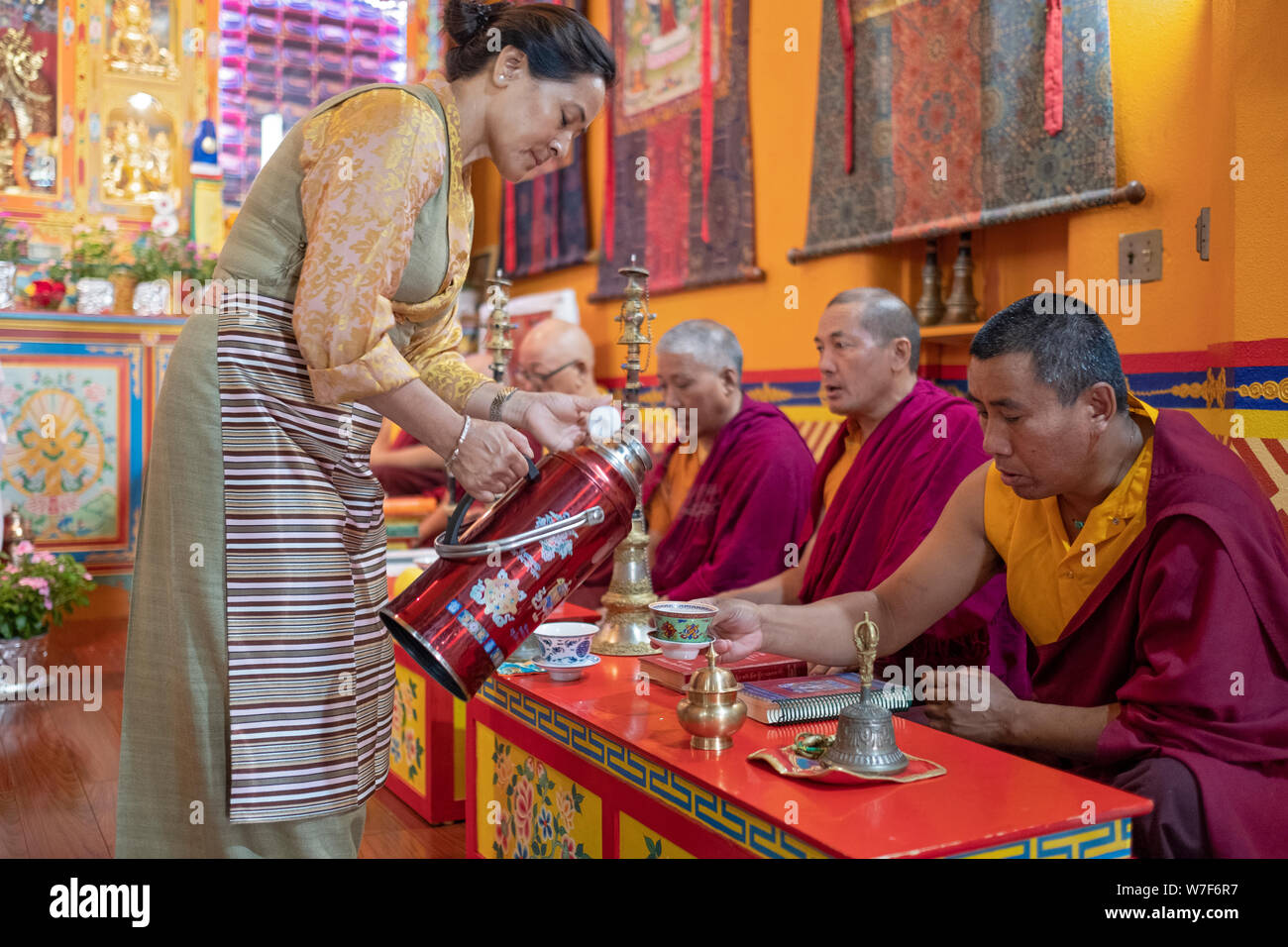 Eine attraktive Nepalesische Frau giesst Kaffee für die Mönche, die an der Sherpa Kyidug Tempel in NEW YORK führenden sind ein morgengebet Service. Stockfoto