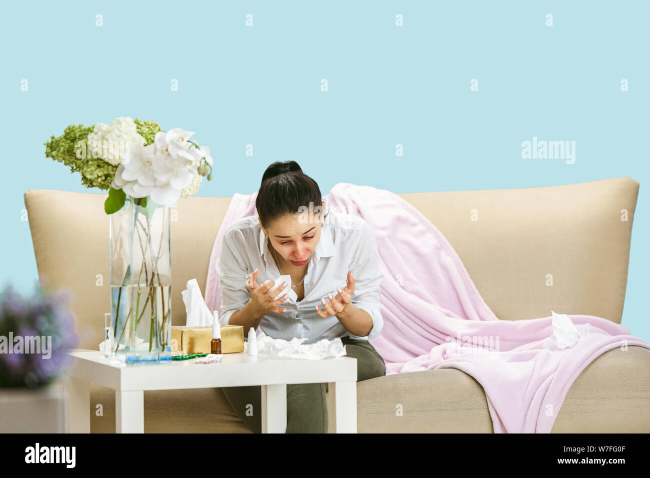 Junge Frau mit hausehold Staub oder saisonale Allergien. Niesen in der Serviette und sitzt von gebrauchten Servietten auf dem Boden und einem umgeben. Arzneimittel ohne Ergebnis. Healthcare Konzept. Stockfoto