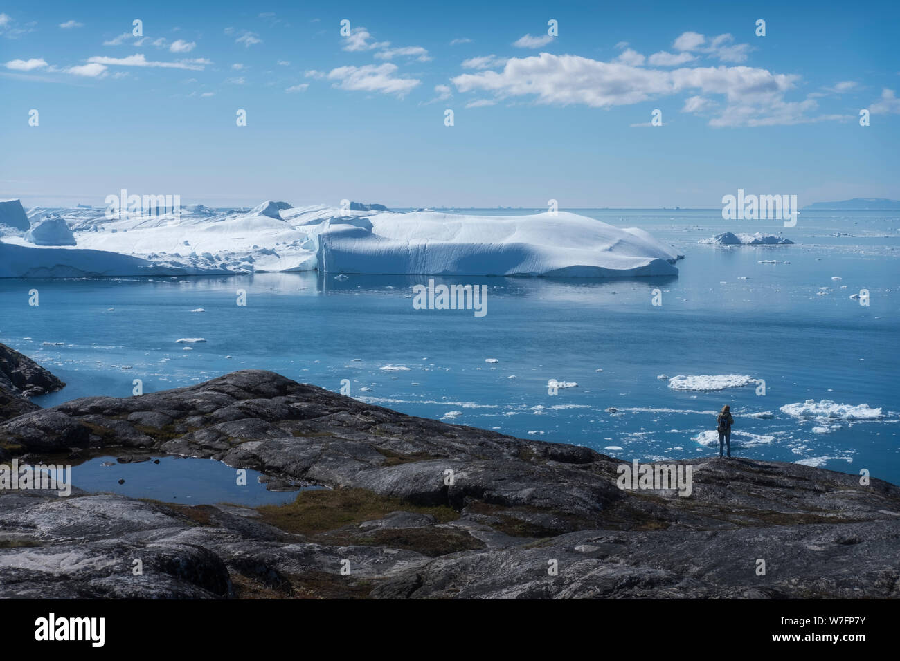Klimawandel in Grönland. Tourist, der sich schmelzende Eisberge ansieht. Stockfoto