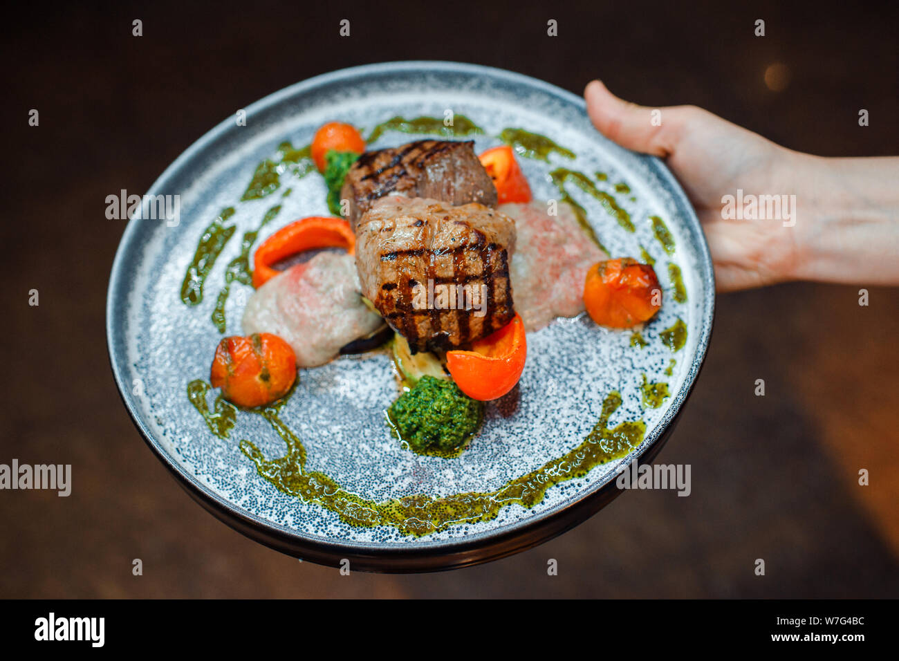 Mitte - gebratenes Fleisch mit Gemüse auf blauem Teller in einem Restaurant. Stockfoto