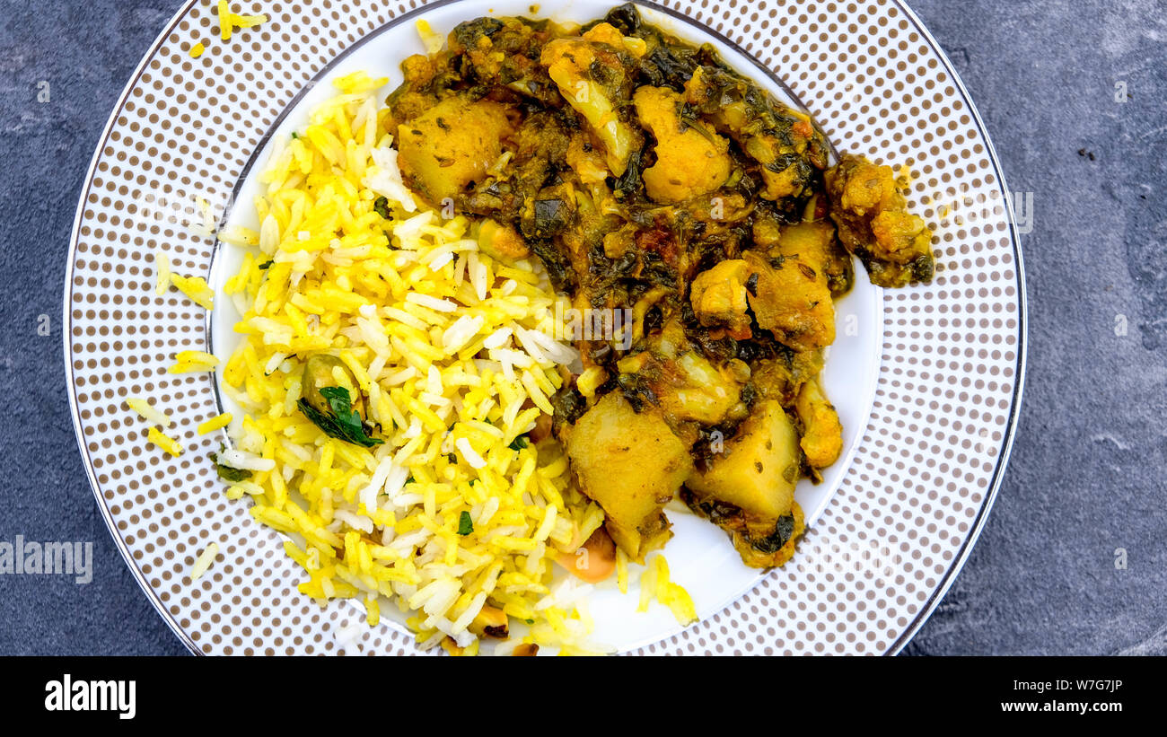 Im indischen Stil vegetarische Aloo Gobi Saag, Kartoffeln, Blumenkohl und Spinat in pikanter Soße mit Reis Stockfoto