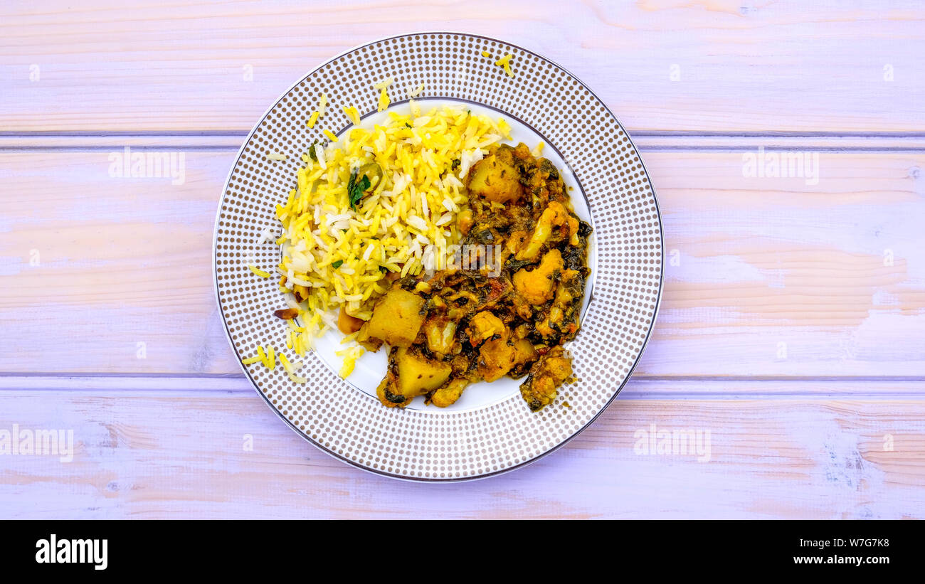Im indischen Stil vegetarische Aloo Gobi Saag, Kartoffeln, Blumenkohl und Spinat in pikanter Soße mit Reis Stockfoto