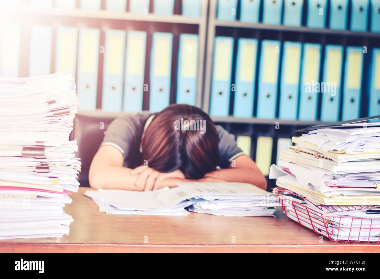 Verschwommen Business Frau schlafend auf Büro Schreibtisch an Schreibtisch mit w Schreibarbeit Stapel Dokumente und Finanzen blatt Konzept für überarbeitet oder harte Arbeitslast Stockfoto