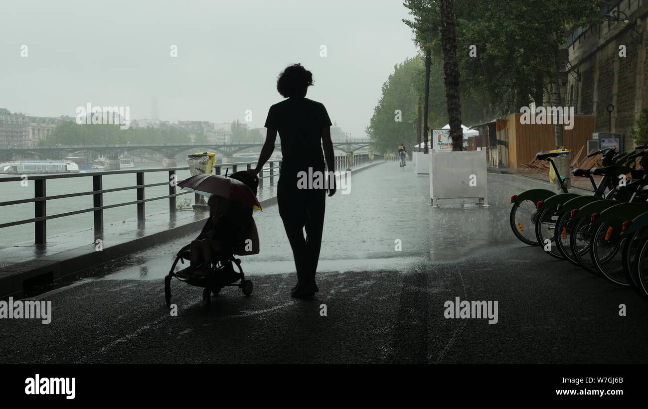 Ein Vater schieben Kinderwagen wartet unter einer Brücke in Paris, als der Regen vorbei. Stockfoto