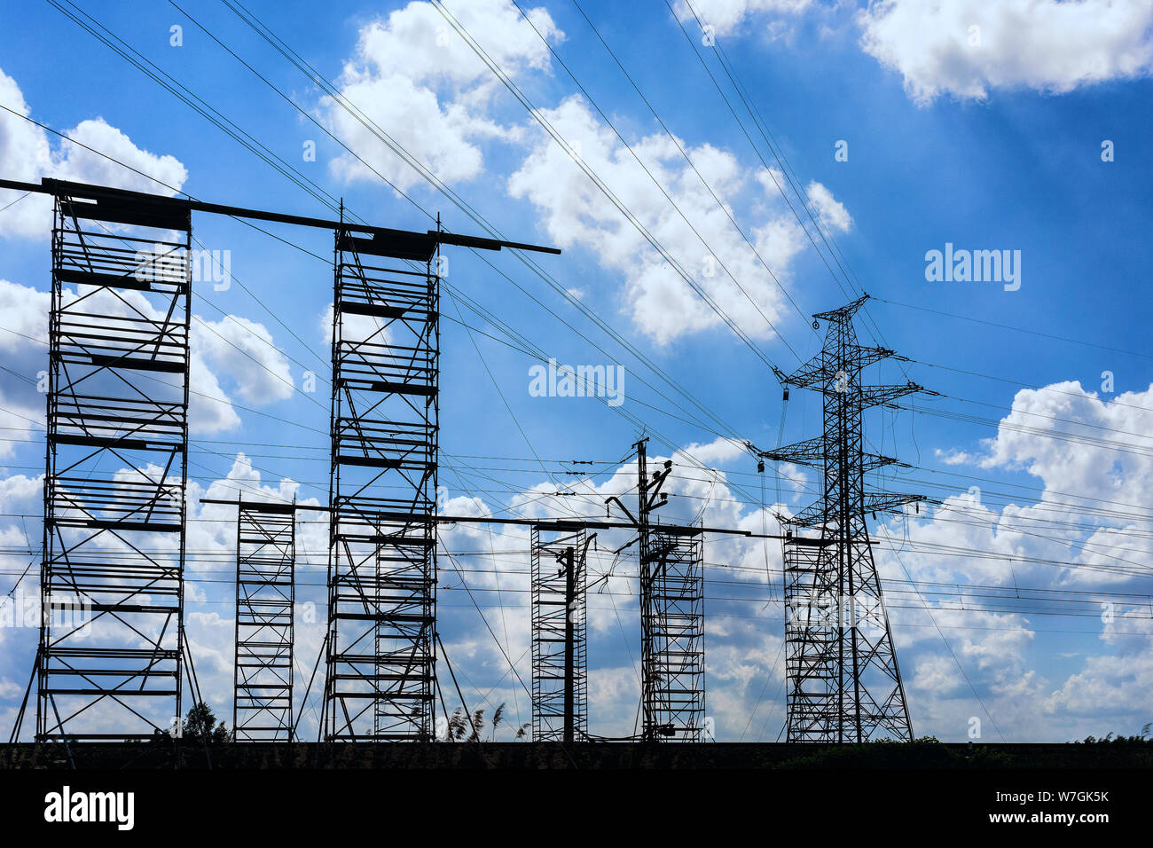 Rotes Auto Kran neben einem neuen Strommast auf dem Hintergrund der Wolken und blauer Himmel Stockfoto