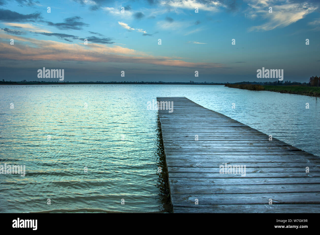 Lange Brücke über den See und den Abendhimmel nach Sonnenuntergang Stockfoto