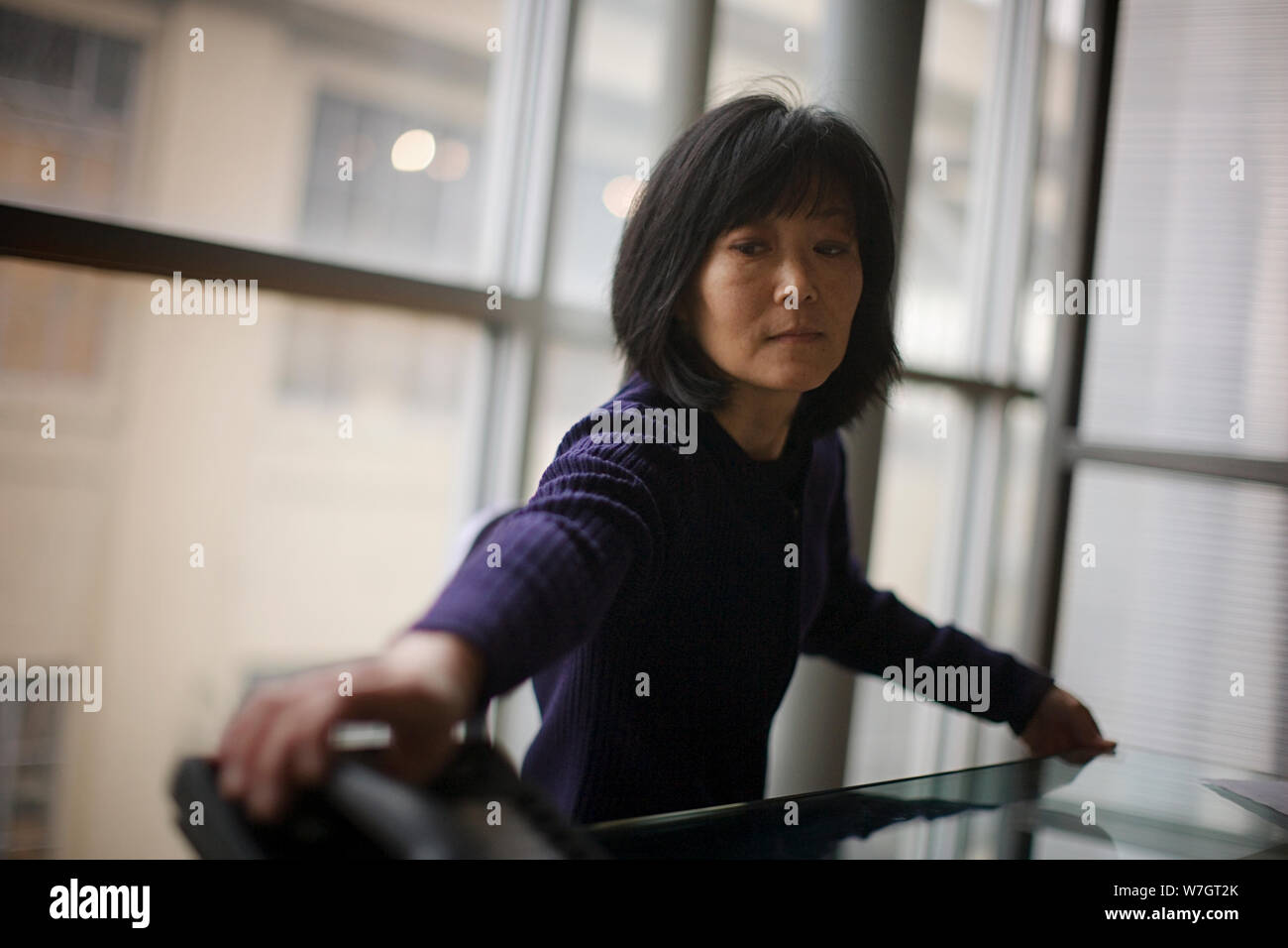 Mitte der erwachsenen Frau entgegen ein Telefon auf dem Tisch in einem Sitzungssaal. Stockfoto