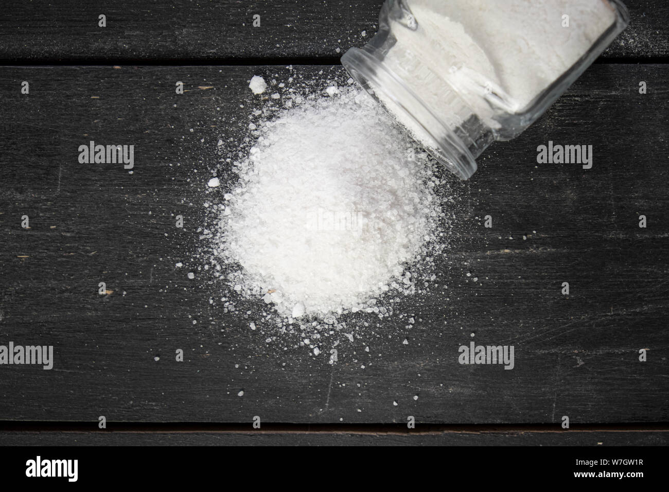 Meersalz in dunklen backfround, Ansicht von oben. Bündel von Salz auf Dunkler Holztisch, Konzept der gesunden Ernährung betrifft, Essgewohnheiten. Stockfoto