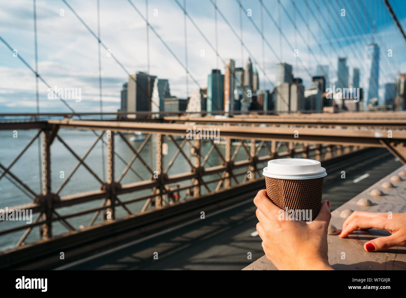 Detail der Hand eines Mädchens mit einem Glas Kaffee, während Sie New York von einer Brücke - Close-up Stockfoto
