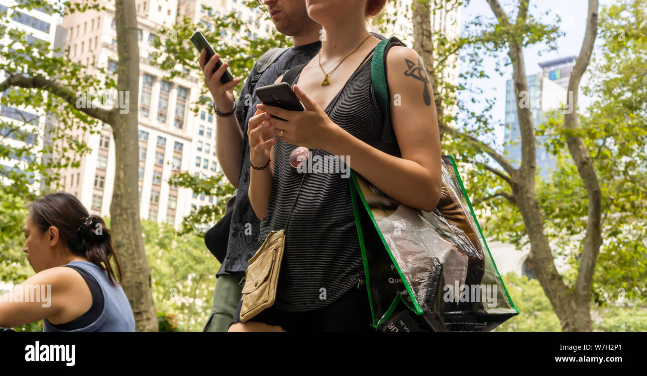 Abgelenkt millennials, auf ihren Smartphones vertieft, im Bryant Park in New York am Donnerstag, den 1. August 2019. (© Richard B. Levine) Stockfoto