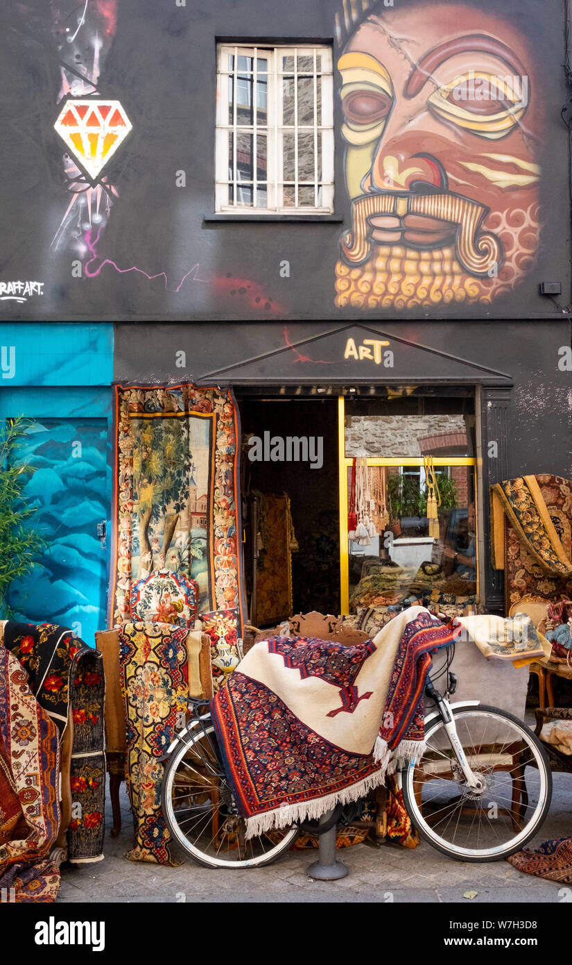 Ein antiker Händler Shop auf dem Flohmarkt in Clignancourt, Paris mit persischen Teppichen und einem Fahrrad außerhalb Stockfoto