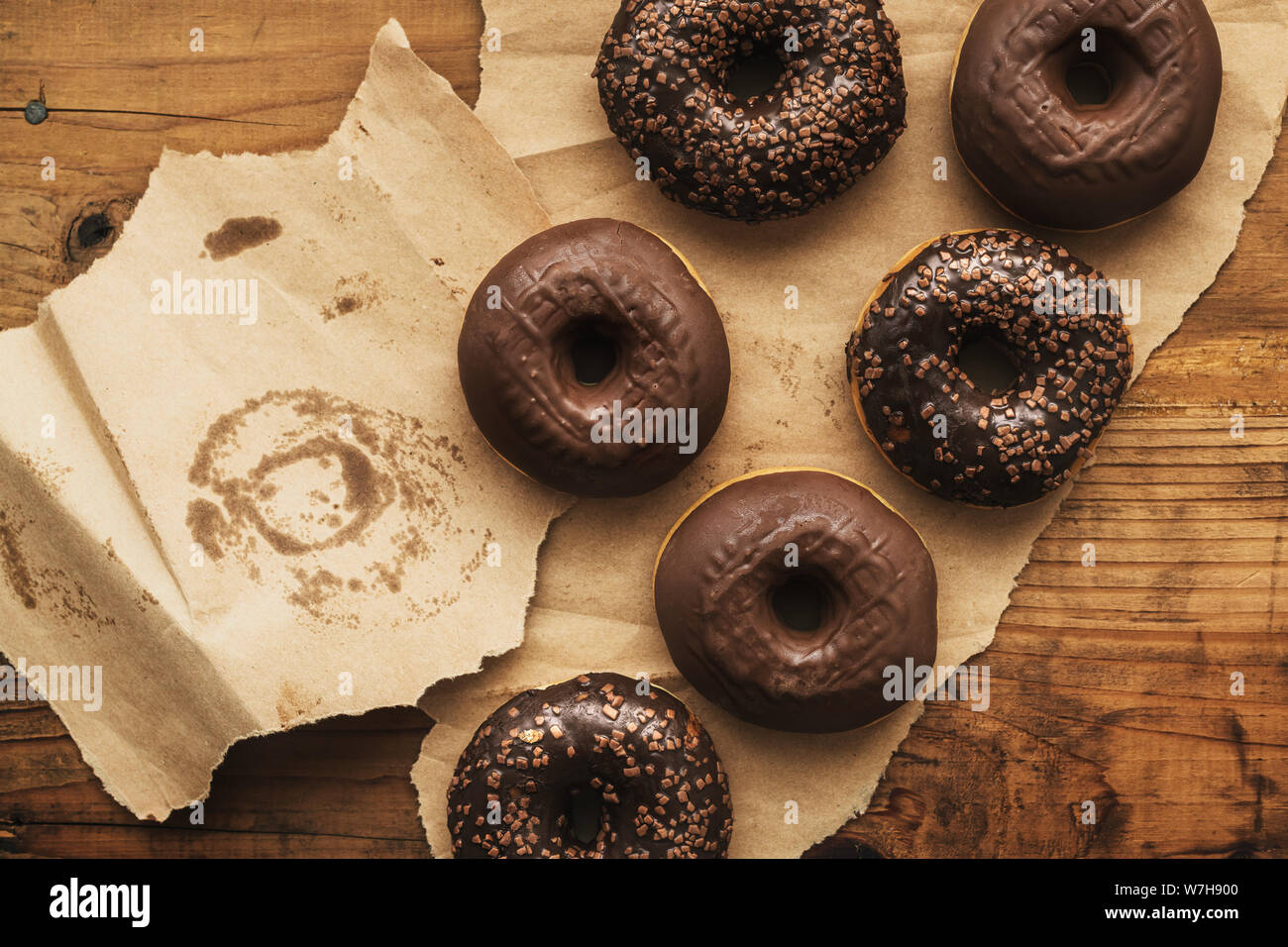 Leckere Schokolade Donuts mit Sahne und Krümel auf rustikalen Holztisch direkt von oben gesehen Stockfoto