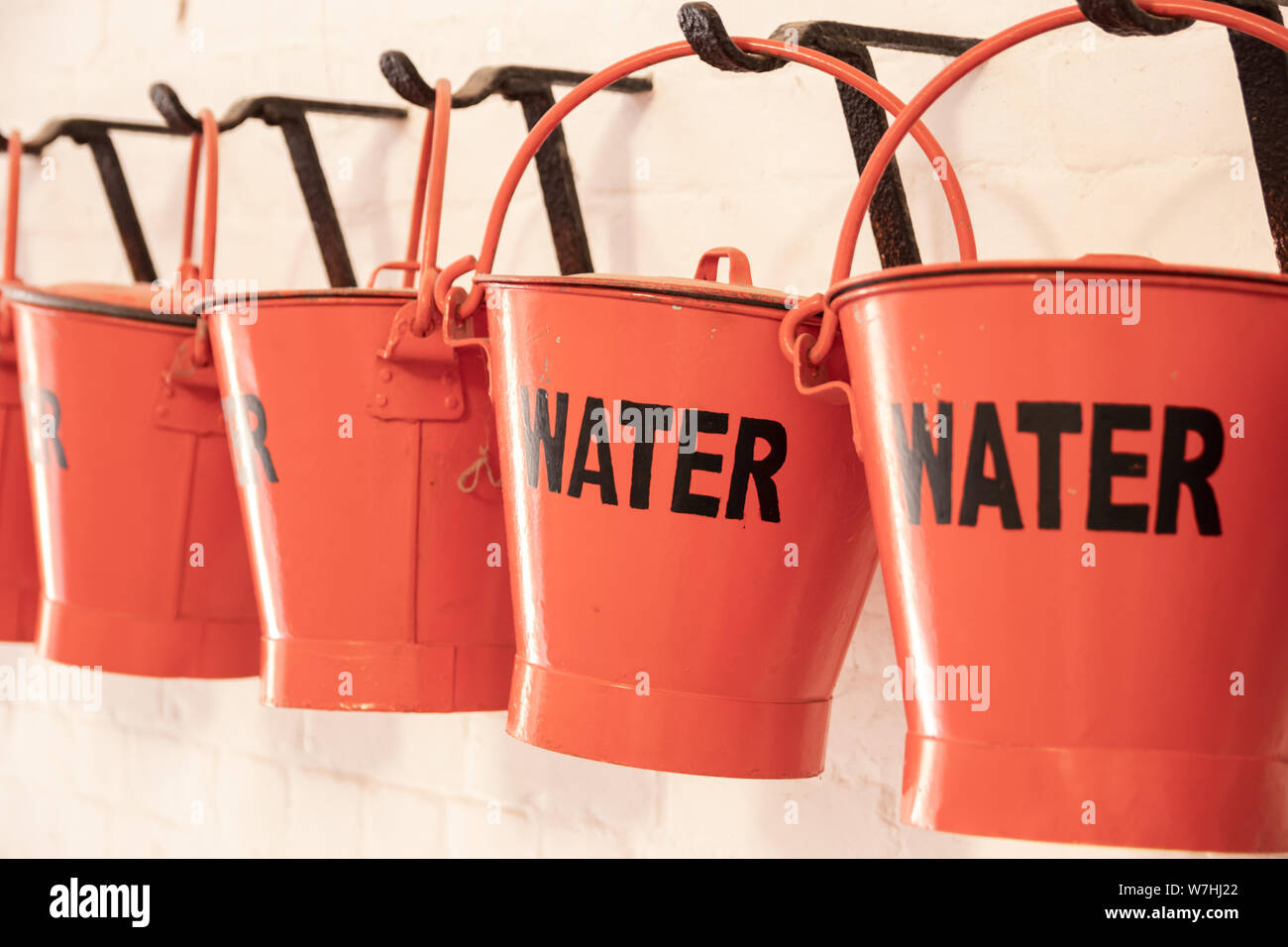 Rote Eimer mit dem Wort Wasser auf der Seite für die Brandbekämpfung Stockfoto