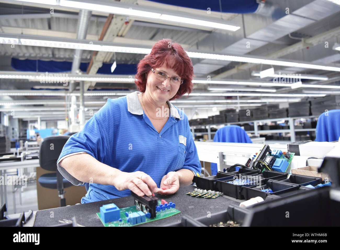 Freundliche Frau in einem mikroelektronikfertigung Factory-Komponenten Montage und Löten arbeiten Stockfoto