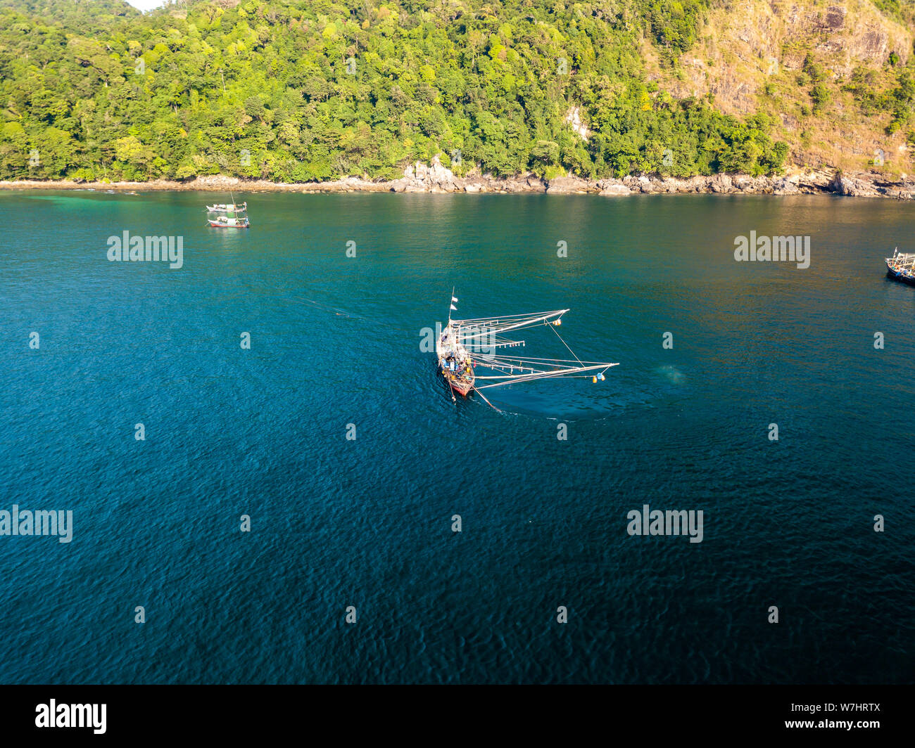 Eine traditionelle burmesische Fischerboot günstig in einer seichten Bucht neben einem Dschungel bedeckten tropischen Insel. Stockfoto