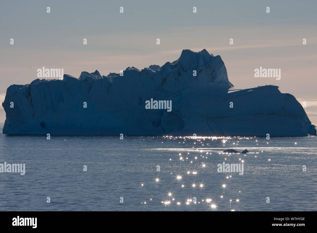 Blendenden Licht Tanz auf den seichten Wellen vor einem riesigen Eisberg in der Bucht um Sydkap, Grönland. Stockfoto