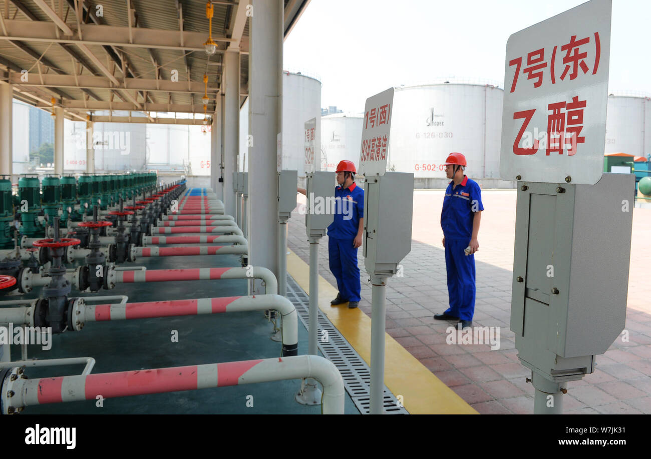 Die chinesischen Arbeiter Kraftstoffleitungen prüfen von ethanol Benzin, rechts, und andere Arten von Benzin an einer Tankstelle von Sinopec (China Petroleum & Chemical Corporation Stockfoto