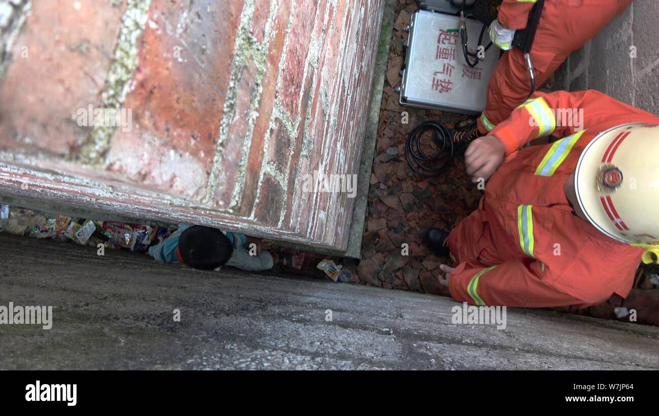 Chinesische Feuerwehrleute versuchen, den neun Jahre alten chinesischen Jungen zu retten, mit dem Beinamen Huang immer stecken in einem Raum so schmal wie 20 Zentimeter zwischen Wänden in Stockfoto