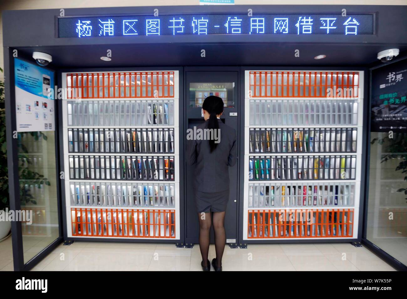 Ein Bürger verwendet, um die Maschine zu Bücher kostenlos vor einem gemeinsamen Bücherregal betrieben von zhima Credit von Alibaba Ant Finanzielle, Shanghai Yangpu ausleihen Stockfoto
