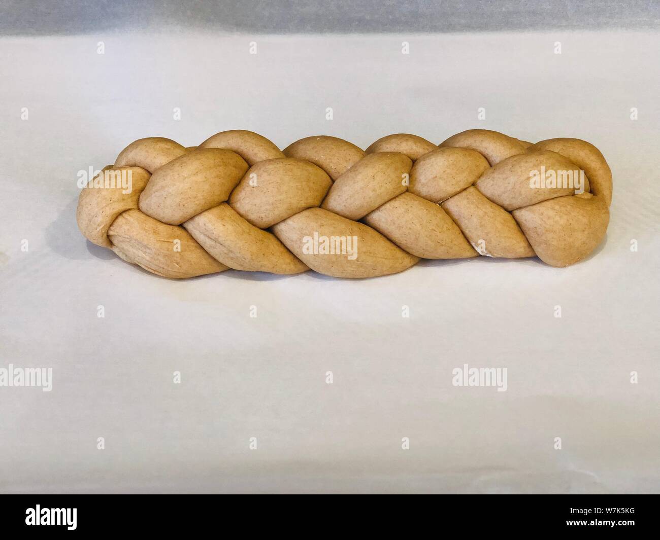 Sichern hausgemachte challah Brot geflochtene Teig vor seinem auf einem Trägermaterial Papier gesichert Stockfoto